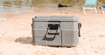 two people sitting in beach chairs with a Rugged Road beach cooler in between them