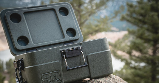 green rugged road cooler sitting on a rock